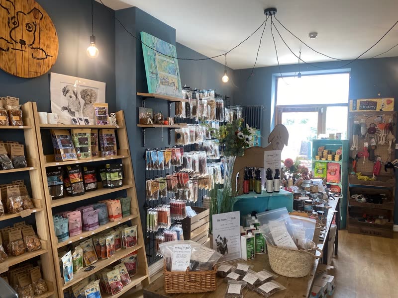Inside the shop: wooden shelving stacked with dog treats, food and accessories, counter at the back