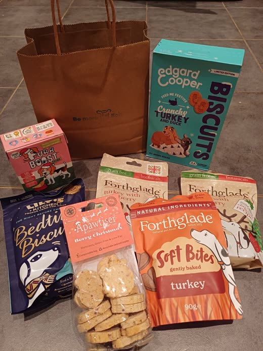 Dog treat boxes and biscuit packets beside a brown paper gift bag